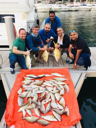 Group of anglers with a large catch of fish on a fishing boat in Dubai Marina