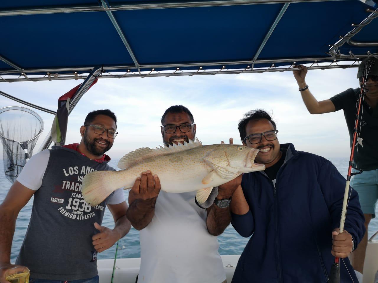 Group of anglers holding a grouper on a deep sea fishing trip in Dubai